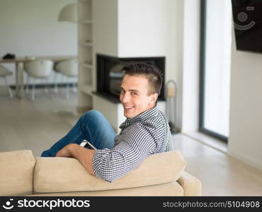 young happy man on sofa using tablet computer at luxury home