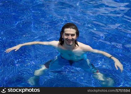 Young happy man smiling on a pool with clear blue water