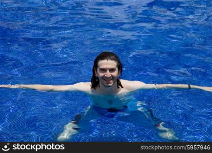 Young happy man smiling on a pool with clear blue water