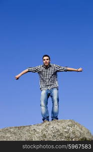 young happy man, starting a big jump, on top of a rock