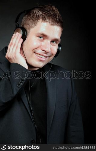 Young happy man student with headphones listening to music black grunge background