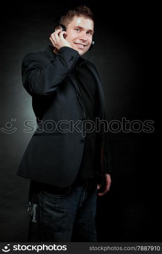 Young happy man student with headphones listening to music black grunge background