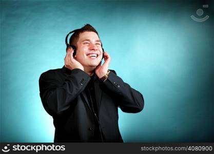 Young happy man student with headphones listening to music blue background