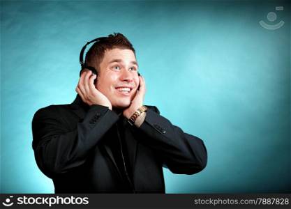 Young happy man student with headphones listening to music blue background