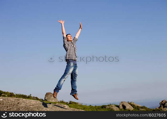 young happy man, with a big jump, on top of a rock