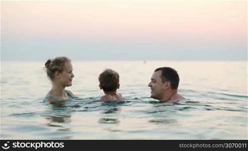 Young happy mother, father and little son bathing in sea. Family summer vacation