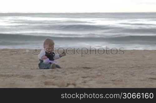Young happy mother plays with her son on the beach.