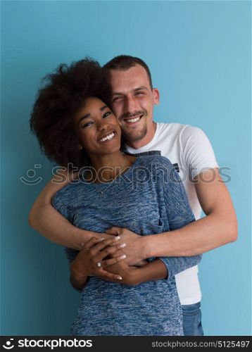 Young happy multiethnic couple laughing and hugging isolated on a blue background