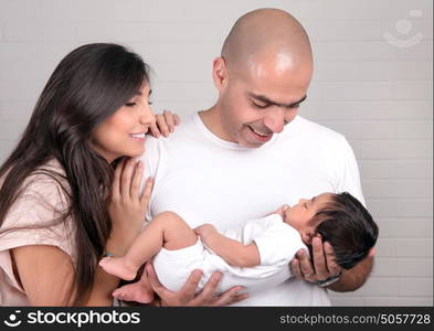 Young happy parents looking on their little newborn baby, having fun at home, enjoying life, new loving family concept