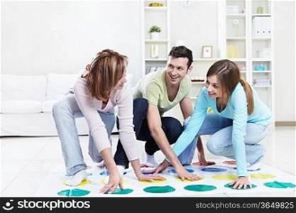 Young happy people playing twister at home