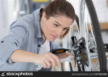 young happy positive woman master is repairing bicycle in workshop