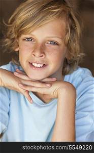 Young happy smiling blond boy child aged about 12 or early teenager resting on his hands
