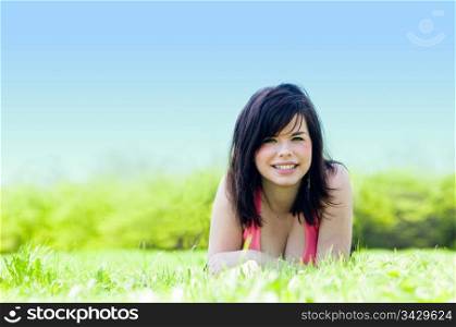 Young happy smiling girl lying on grass