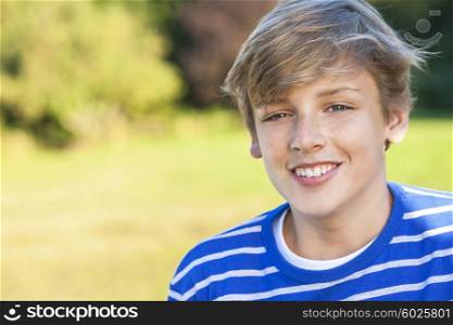 Young happy smiling male boy teenager blond child outside in summer sunshine wearing a blue sweatshirt