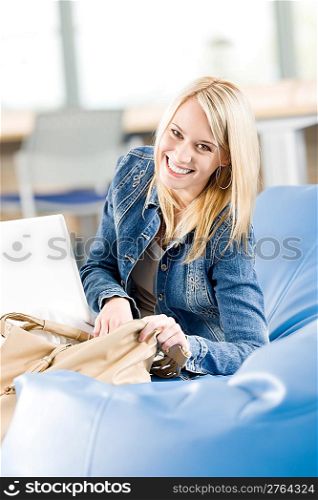 Young happy student girl at high school relaxing with laptop