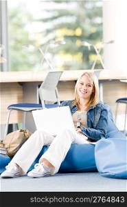Young happy student girl relaxing at high school with laptop