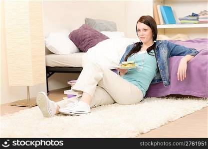 Young happy student have sandwich sitting in student apartment