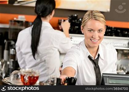 Young happy waitress cashier giving coffee in cafe
