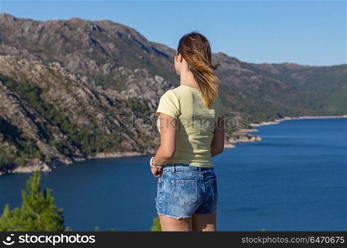 Young happy woman at the mountain, relaxing and enjoying the lake at Geres, Portuguese National Park. girl enjoying the lake