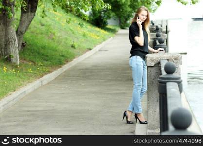 Young happy woman calling by phone on the street