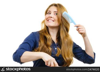 Young happy, woman combing long healthy brown hair, using comb. Woman long healthy brown hair holds comb