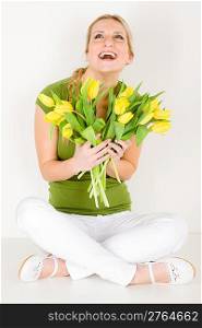 Young happy woman hold bunch of tulips flowers sitting