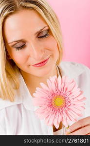 Young happy woman hold pink gerbera daisy looking at blossom