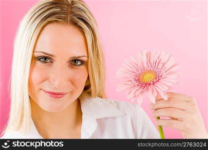 Young happy woman hold pink gerbera daisy looking at camera
