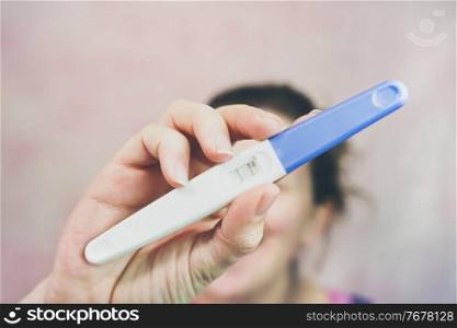 Young happy woman holding a positive pregnancy test                               