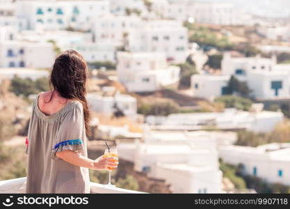 Young happy woman in outdoor cafe with tasty drink. Caucasian tourist enjoy european holidays with amazing view of old city in Greece. Young happy woman in outdoor cafe with tasty drink.