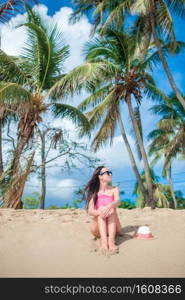 Young happy woman in swimsuit on white beach. Young slim woman on tropical beach under the palm tree in shallow water