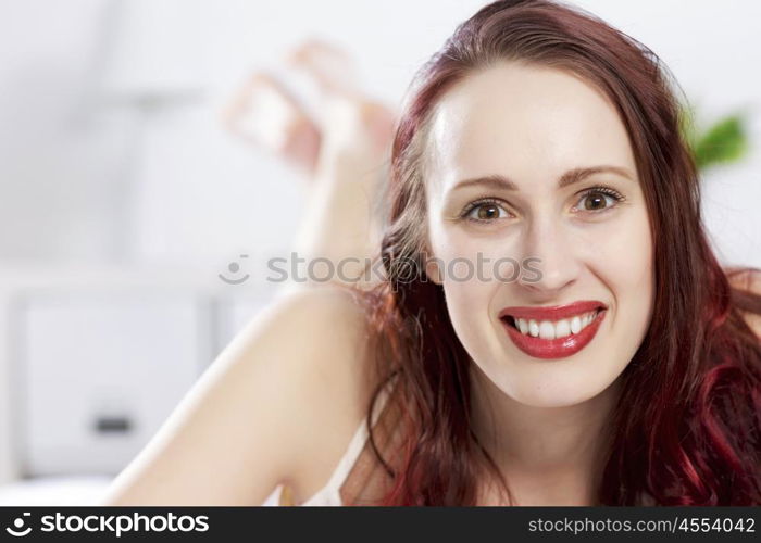 Young happy woman lying in bed and smiling. Good morning