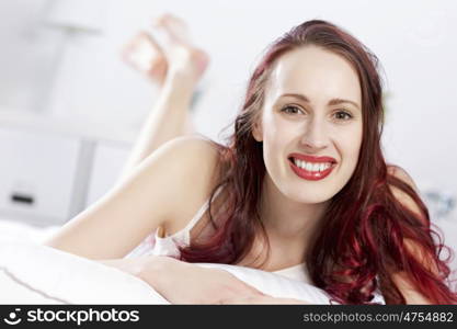 Young happy woman lying in bed and smiling. Good morning