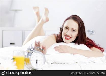 Young happy woman lying in bed and smiling. Good morning