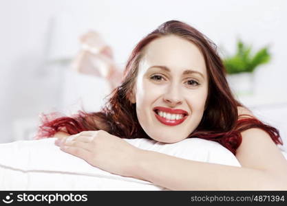 Young happy woman lying in bed and smiling. Good morning