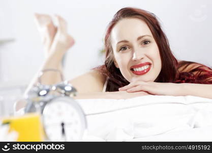 Young happy woman lying in bed and smiling. Good morning