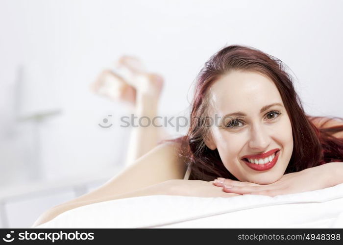 Young happy woman lying in bed and smiling. Good morning