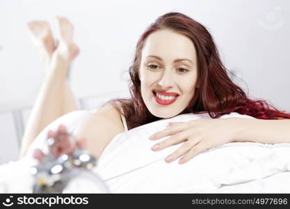 Young happy woman lying in bed and smiling. Good morning