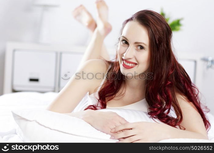 Young happy woman lying in bed and smiling. Good morning