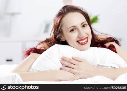 Young happy woman lying in bed and smiling. Good morning