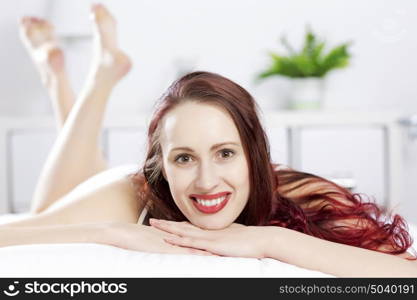 Young happy woman lying in bed and smiling. Good morning