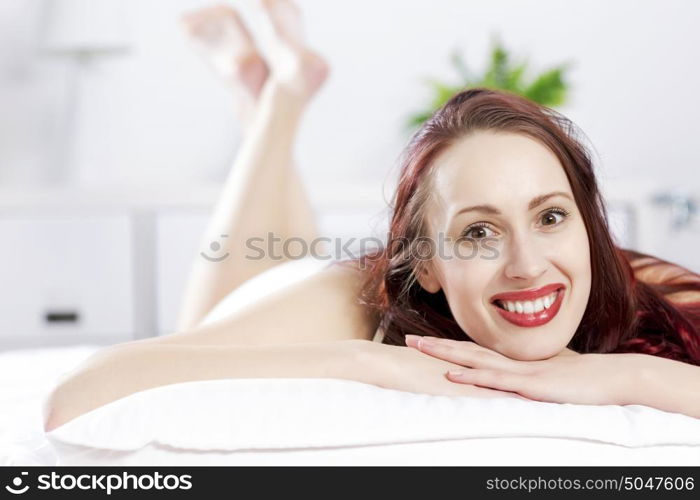 Young happy woman lying in bed and smiling. Good morning