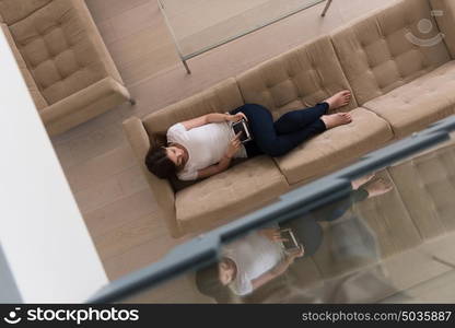 young happy woman on sofa using tablet computer at luxury home