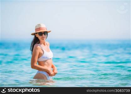 Young happy woman on white beach. Happy girl background the blue sky and turquoise water in the sea. Young beautiful woman having fun on tropical seashore. Happy girl background the blue sky and turquoise water in the sea