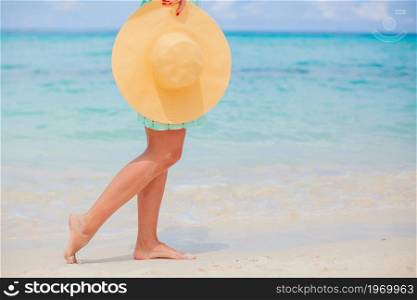 Young happy woman on white beach walking. Closeup of yellow hat. Happy girl background the blue sky and turquoise water in the sea