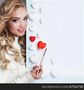 Young happy woman painting in red decorative hearts, Valentines day concept