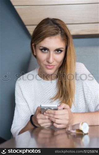 young happy woman sitting at the table and using mobile phone at luxury home