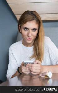 young happy woman sitting at the table and using mobile phone at luxury home