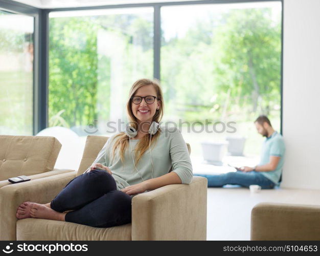 young happy woman sitting on sofa and using mobile phone at luxury home