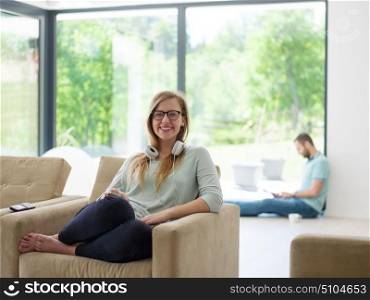 young happy woman sitting on sofa and using mobile phone at luxury home